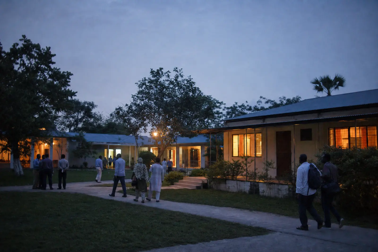 A residential venue at dusk, with participants moving between buildings.